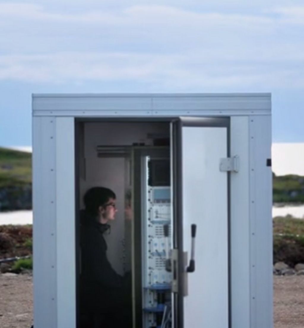 Ung mann sitter i en kontainer som er plassert ved like ved havet