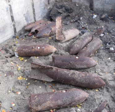 Rustne granater ligger på sandbunn inntil en betongvekk. Ammunisjonen er dumpet og har ligget her siden andre verdenskrig.