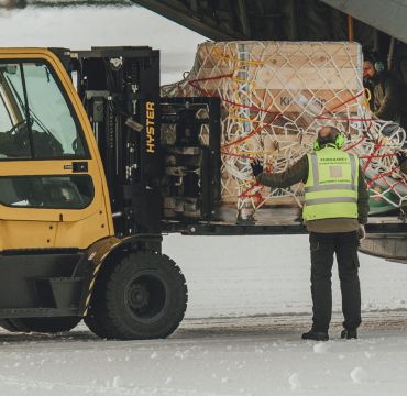 En truck laster av en pall fra lasterampen bak på en C130J-30 Hercules.