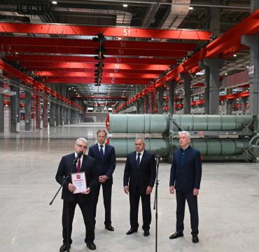Fire dresskledde menn i en industrihall.