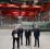 Fire dresskledde menn i en industrihall.