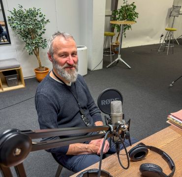 Forsker bak mikrofonen i podkaststudio.