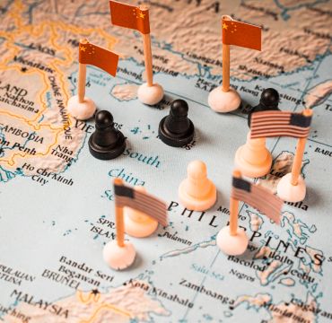 Kinesiske og amerikanske flagg med sjakkbrikker på et kart over Sør-Kina havet. Bildet skal symboliserer konflikten om kontrollen over området.