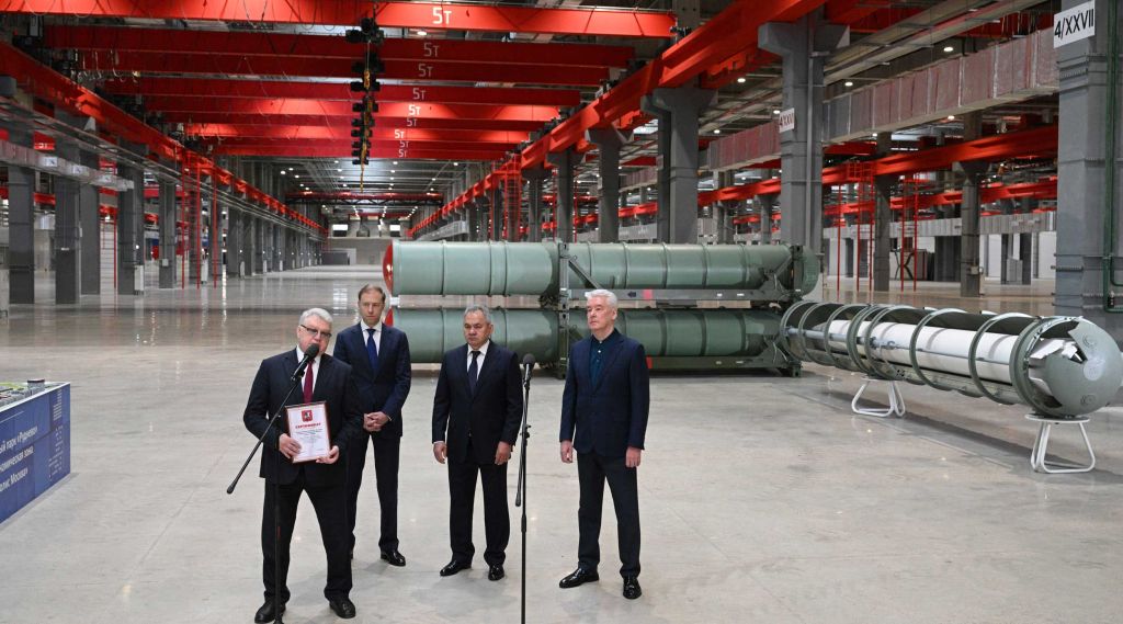Fire dresskledde menn i en industrihall.